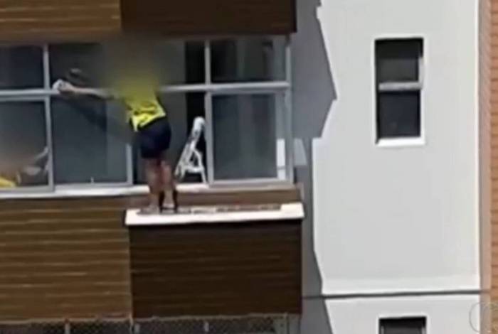 Mulher se arrisca para limpar vidro do lado de fora no 6º andar de prédio
